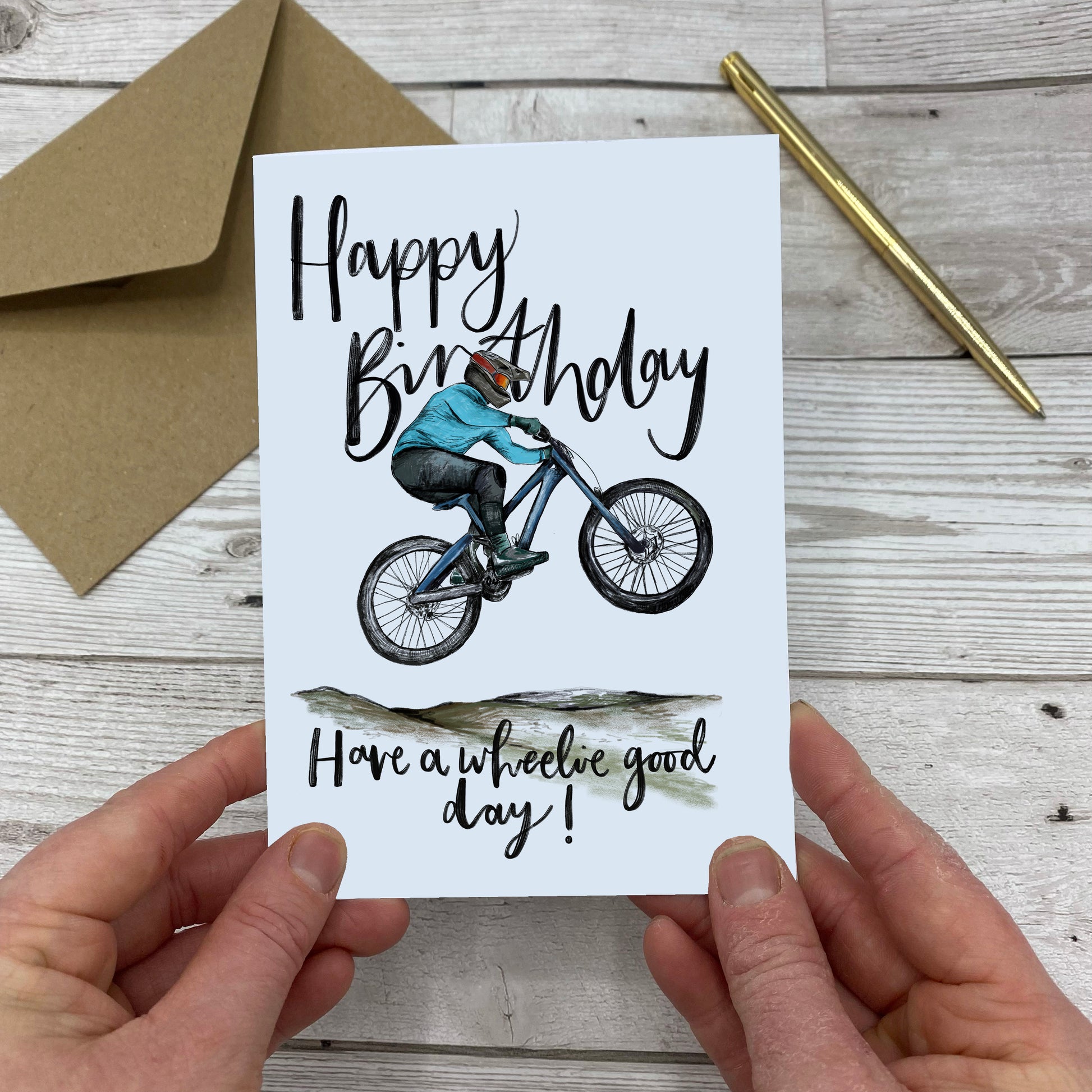 Greetings card with a figure on a mountain bike that reads "Happy Birthday. Have a wheelie good day!"