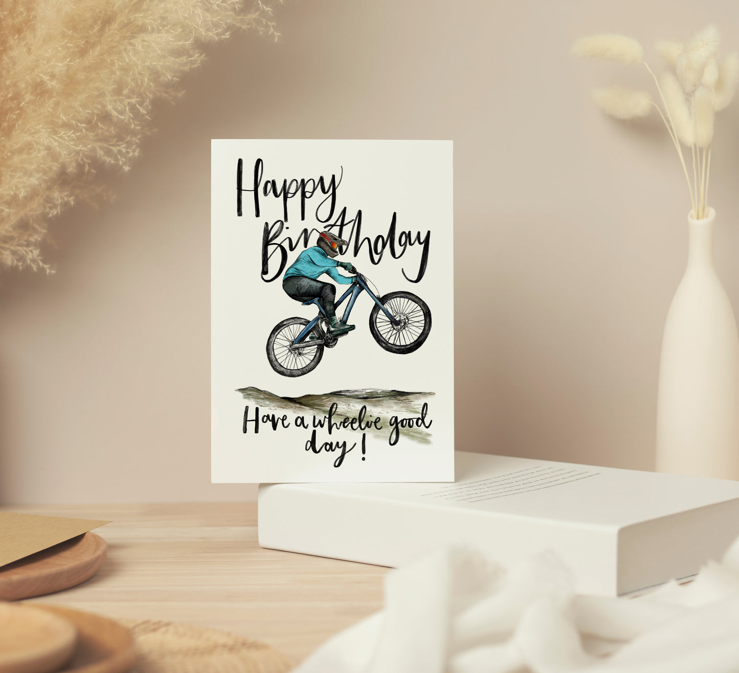 Greetings card with a figure on a mountain bike that reads "Happy Birthday. Have a wheelie good day!"